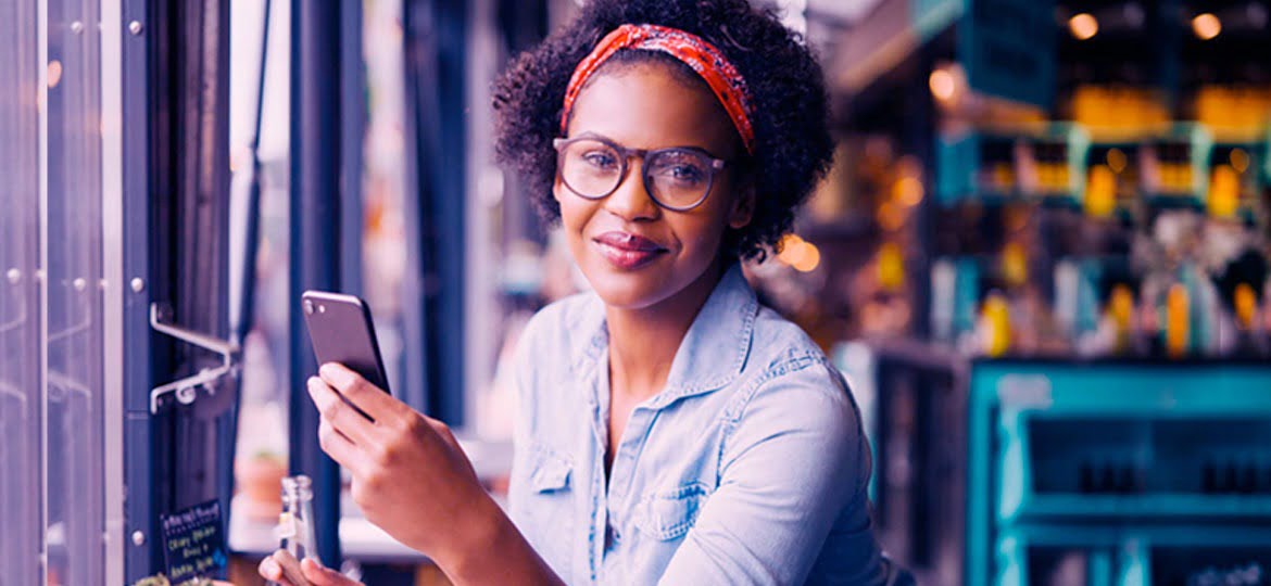 Mulher de óculos e bandana usando smartphone