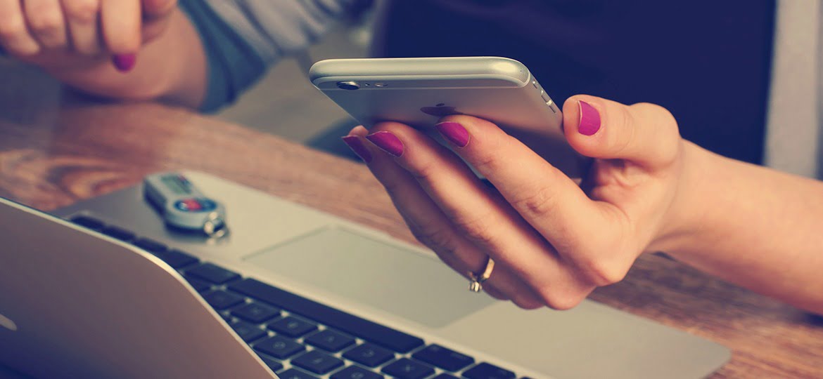 Mulher usando seu smartphone em frente ao notebook